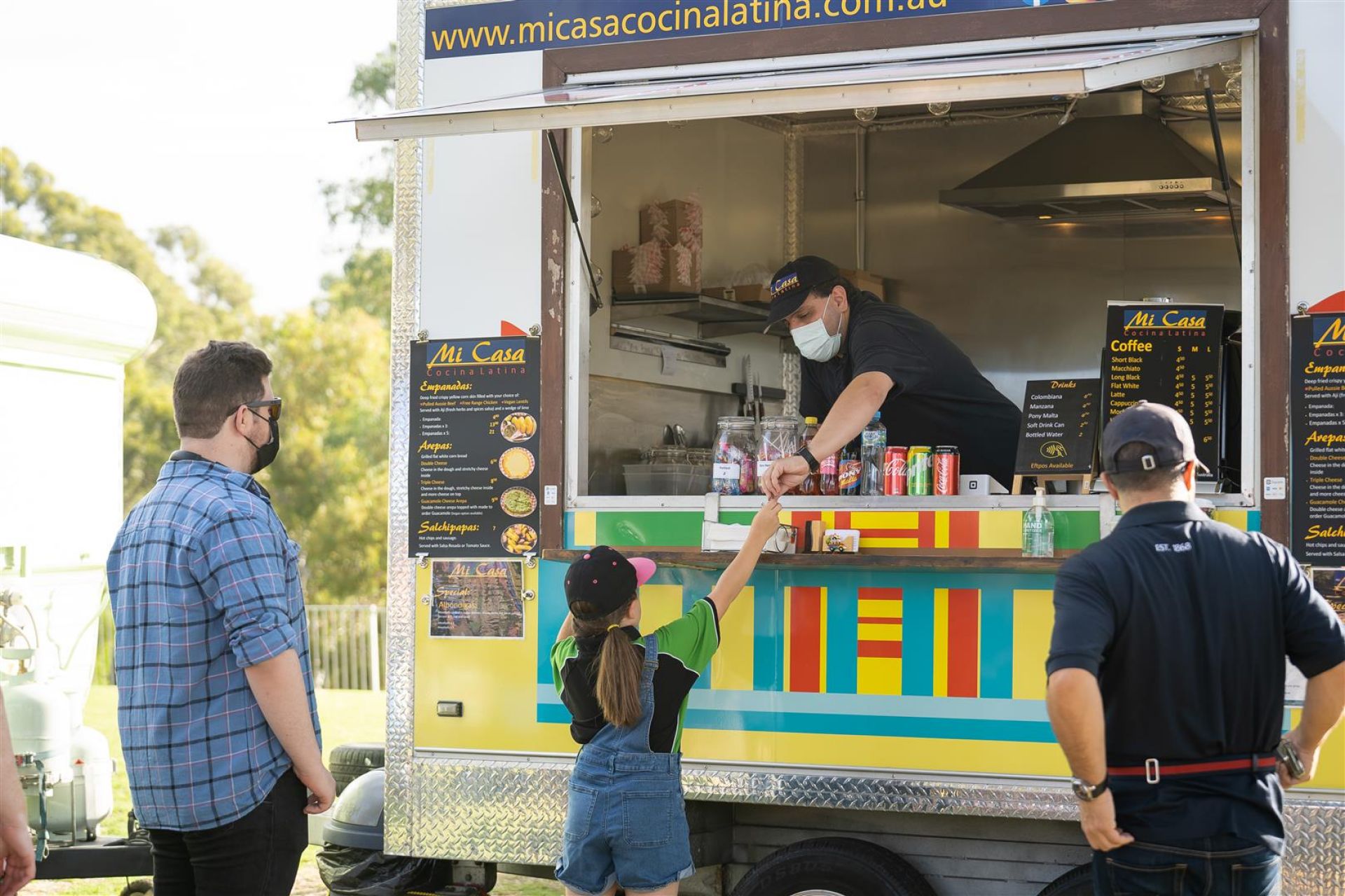 An employee from Mi Casa Latino Cucino serving il Cibo from a food truck