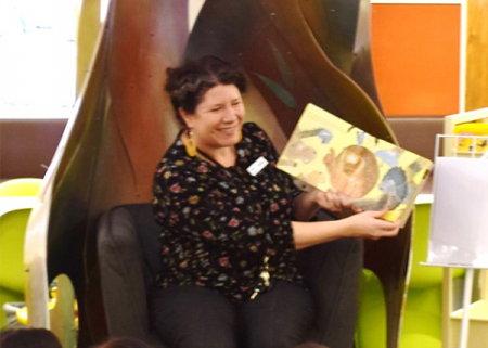 A library staff member holding a book and smiling.