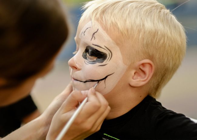 A child getting their face painted for Halloween
