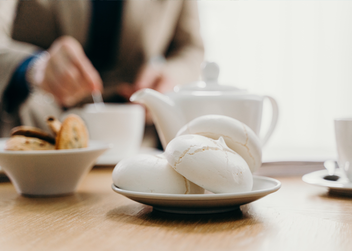 A teapot, cup, saucer and biscuits on a table.
