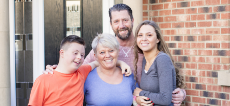 A family with a child with a disability smiling at the camera.