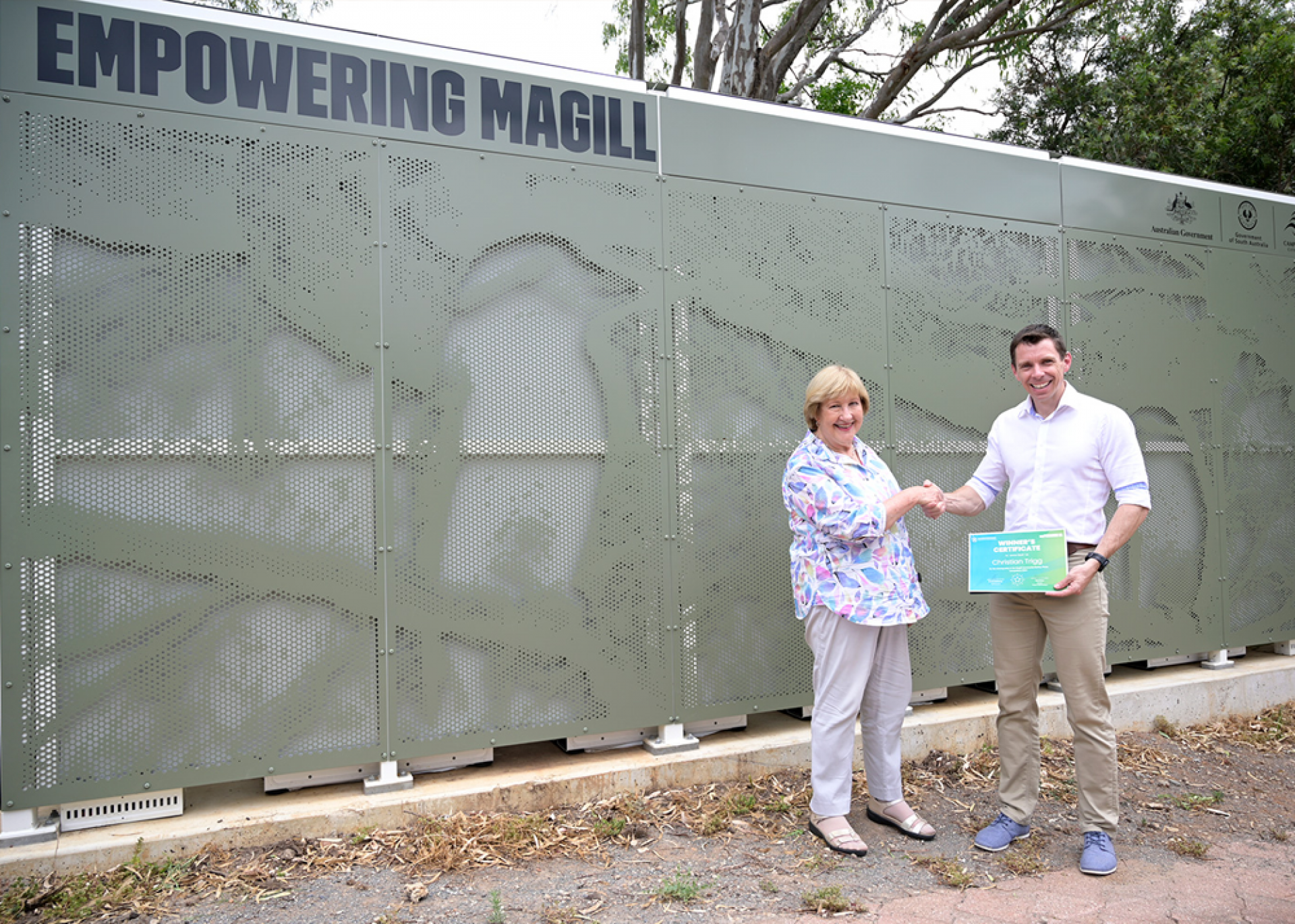 Mayor Jill Whittaker presenting photograph competition winner, Christian Trigg, with a certificate at the Magill Community Battery.