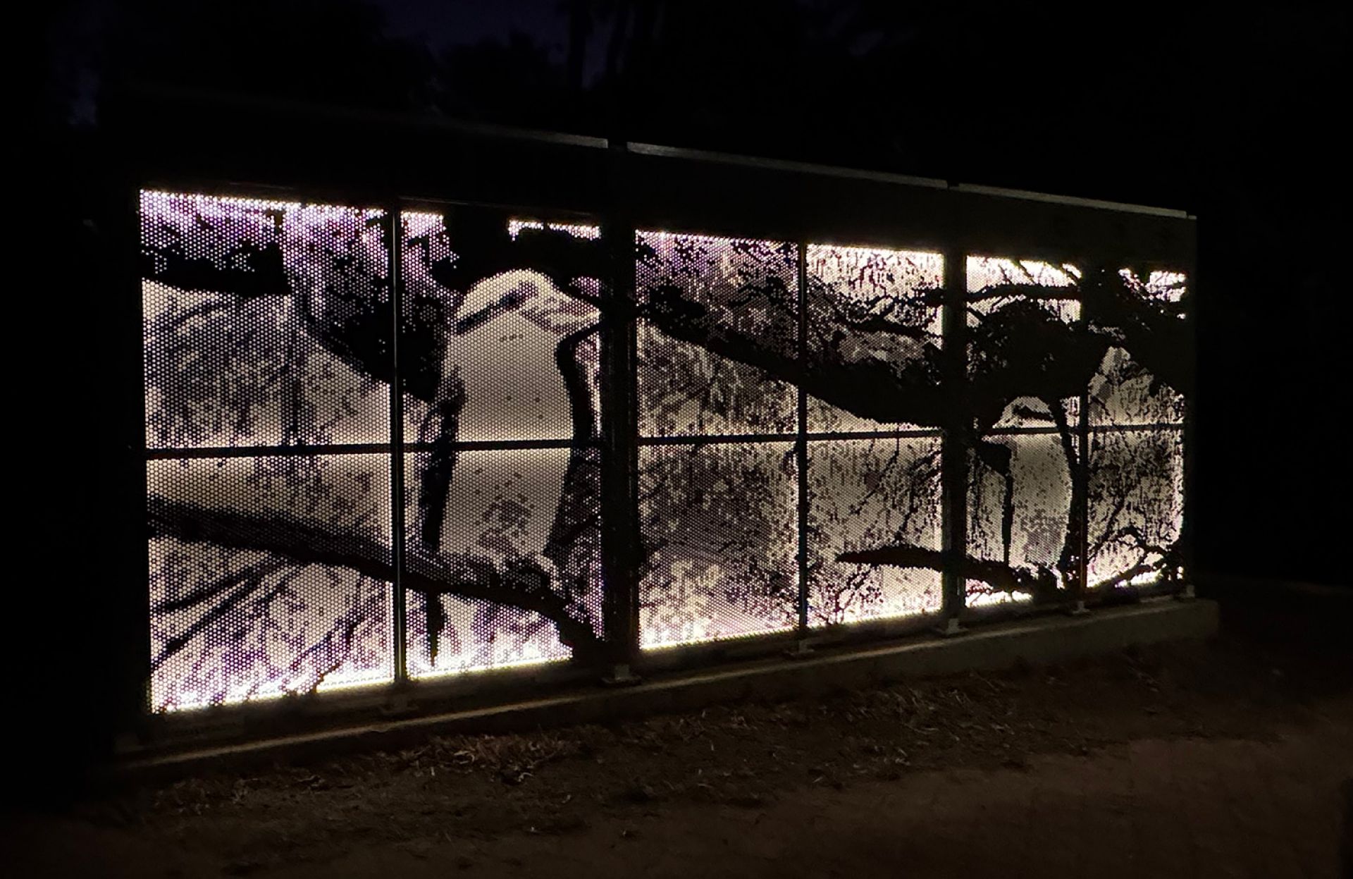 Magill Community Battery at night. The artwork, made from perforated metal, is backlit and depicts a kookaburra.