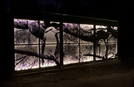 Magill Community Battery at night. The artwork, made from perforated metal, is backlit and depicts a kookaburra.