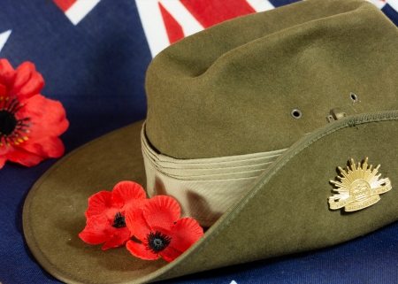 An Australian flag with an army hat and red poppies.