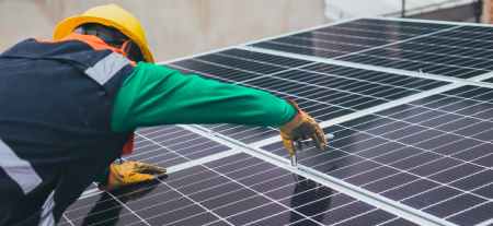 A man installing solar panels on a roof.