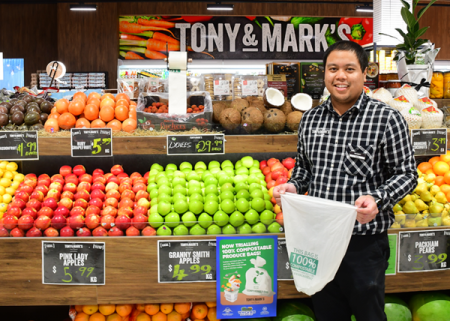 A man holding a compostable produce bag in a fruit and vegetable store.