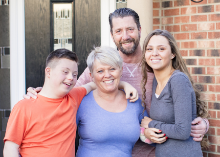 Image of a family smiling with their arms around each other.