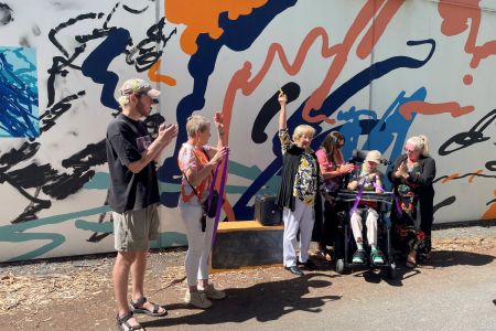 A group of people celebrating the launch of 'Ollie's Mural' at Paradise Recreation Plaza.