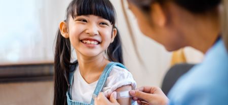 A child smiling with a bandaid on her arm after having an injection.