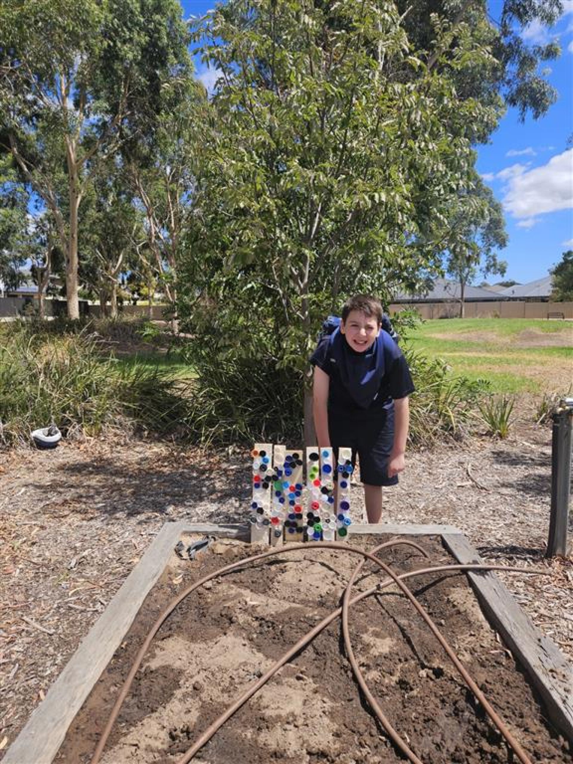 Jayden with his bottle cap artwork in the school garden.