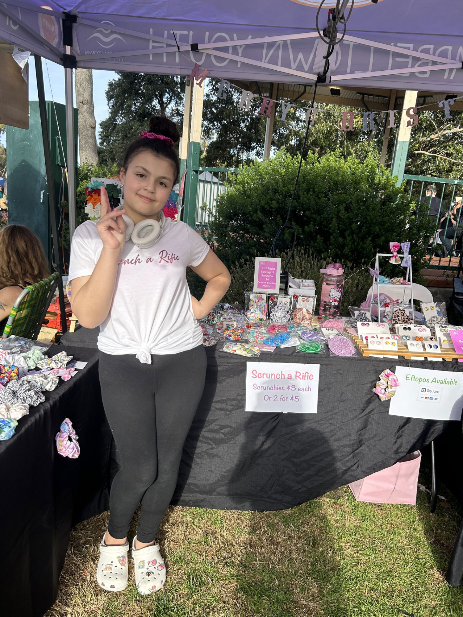 Mariella a 12 year old girl running a scrunchie stall at the Moonlight Markets. She is standing in front of her stall.