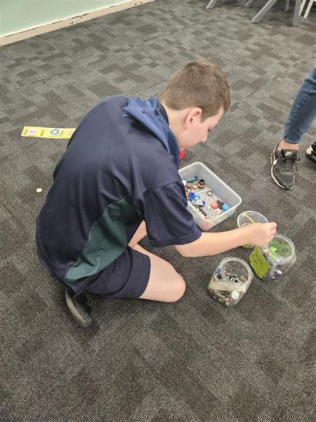 Jayden sorting collected items into metal, plastic and rubber.
