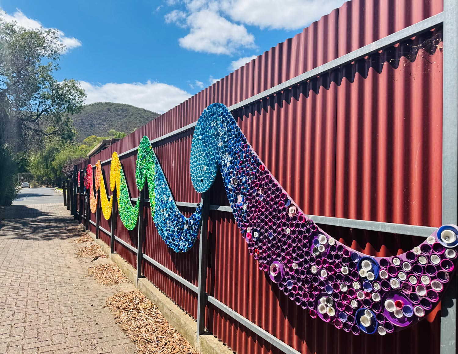 Rainbow inspired bottle cap art in a lane way.
