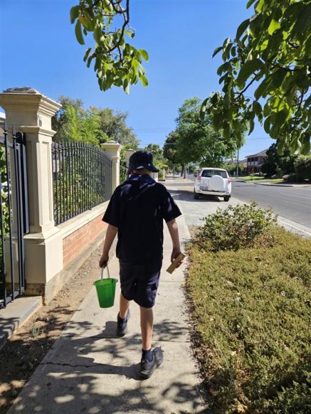 Jayden on a walk through the community collecting rubbish in his bucket.