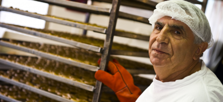 A man wearing a hair net and working in food manufacturing.