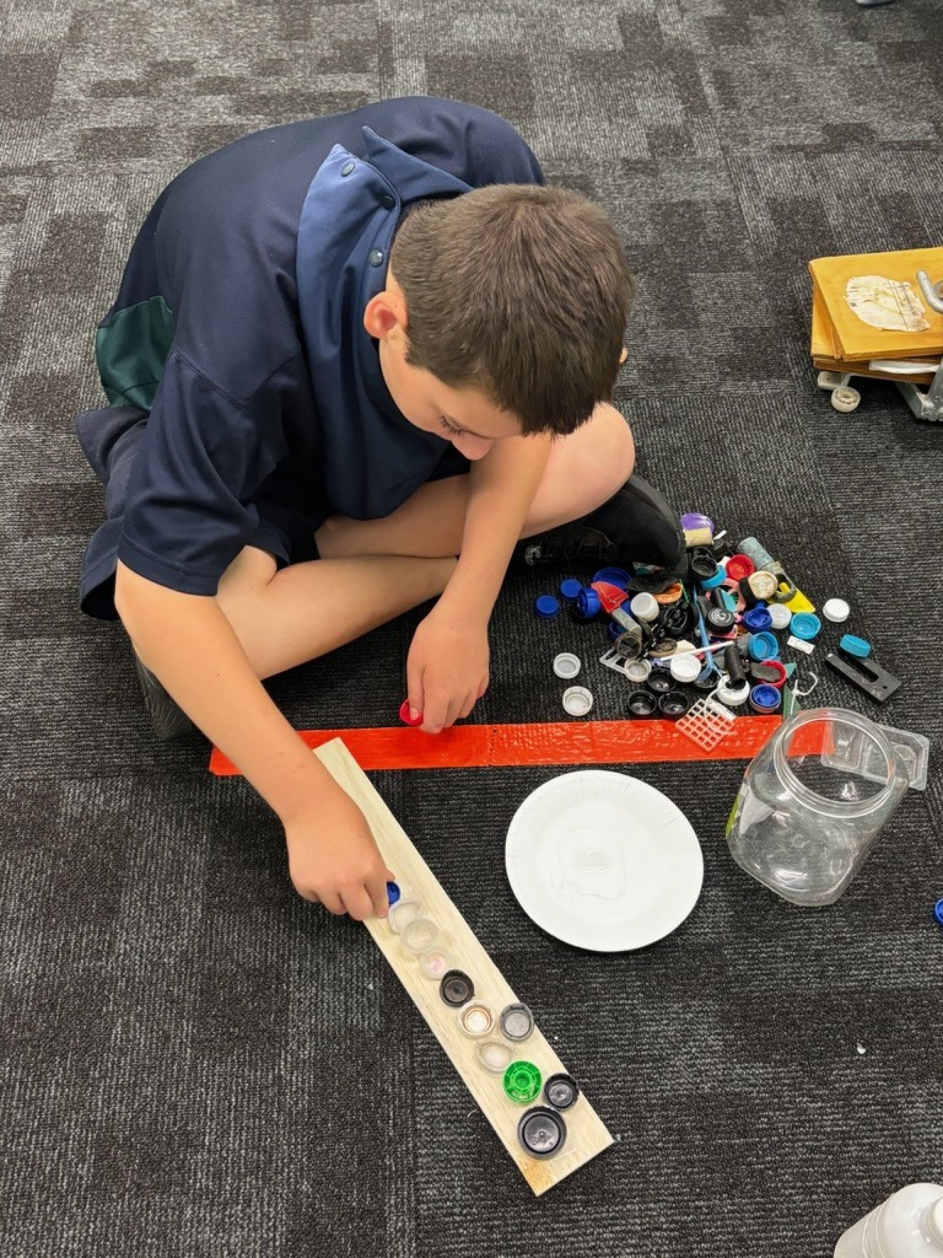 Jayden creating panel artworks using bottle caps.
